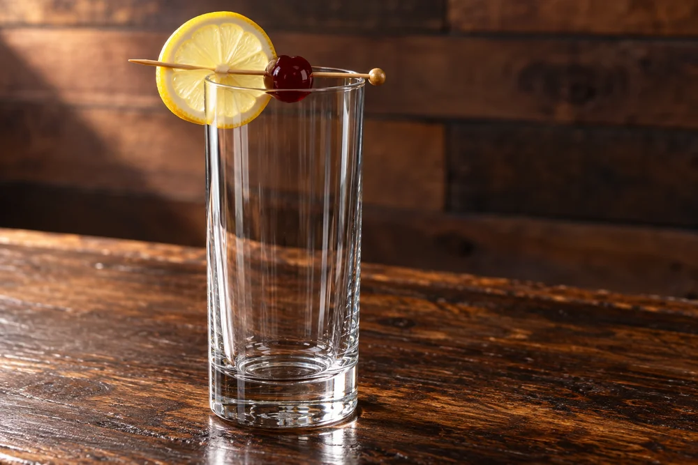 Tom Collins · Garnish on a wooden bar
