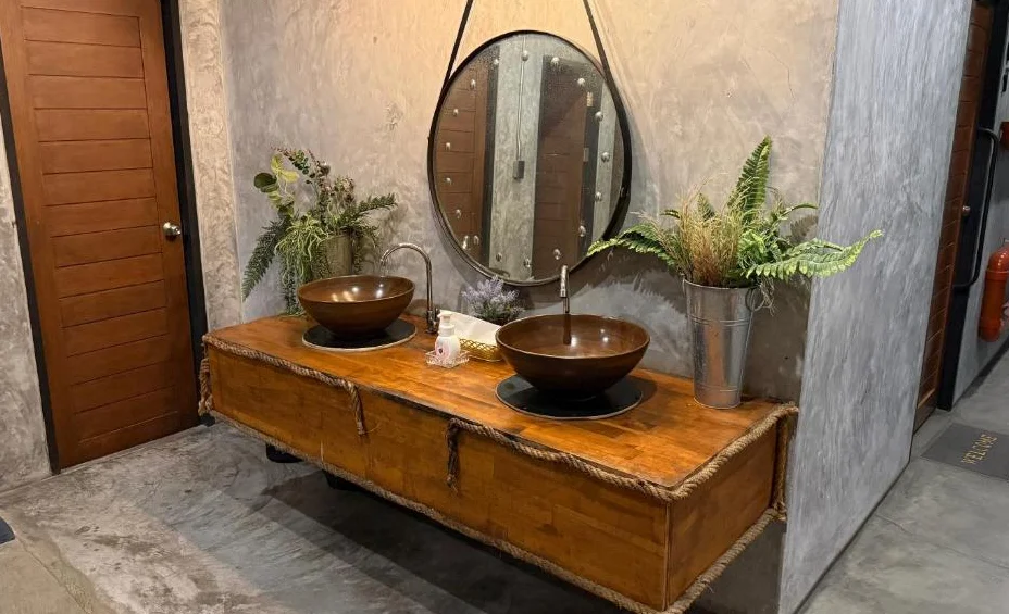 Two washbasins on a wooden counter with a round mirror
